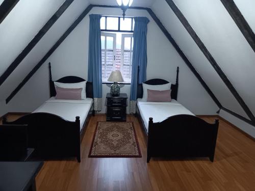 two beds in a attic room with a window at The Bala's Holiday Chalet in Cameron Highlands