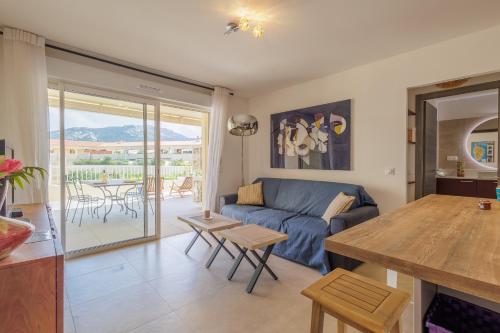 un salon avec un canapé bleu et une table dans l'établissement Le Palmier - Plage à 5 min vue mer et montagne, à Lumio