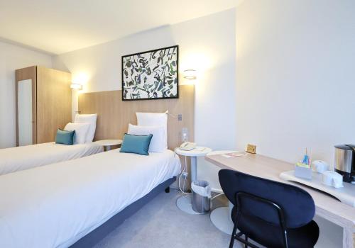 a hotel room with two beds and a desk at Mercure Grenoble Centre Porte des Alpes in Grenoble