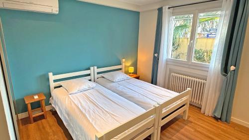 une chambre avec un lit avec un mur bleu dans l'établissement Les Oyats, à Sainte-Maxime