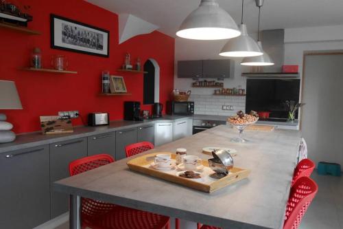 une cuisine aux murs rouges et une table avec des chaises rouges dans l'établissement Location Maison Belle Ile en Mer 10 personnes, au Palais