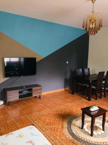 a living room with a television and a table and chairs at Villa SAIDIA climatisée avec PISCINE in Diego Suarez