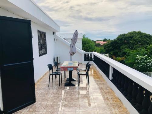 a balcony with a table and chairs and an umbrella at Villa SAIDIA climatisée avec PISCINE in Diego Suarez