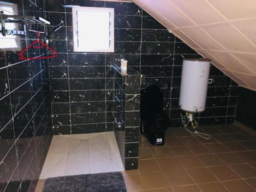 a bathroom with a black tiled wall with a window at Villa SAIDIA climatisée avec PISCINE in Diego Suarez
