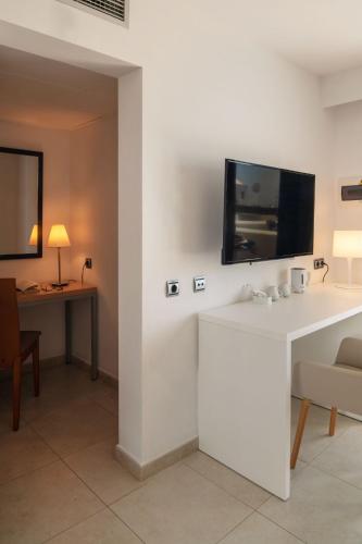 a room with a white counter with a tv on the wall at Hotel Pocillos Playa, solo Adultos in Puerto del Carmen