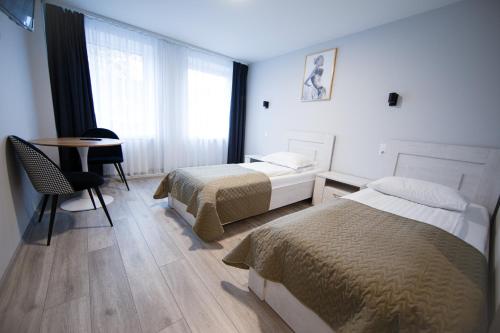 a bedroom with two beds and a desk and a table at Dzukija Hotel in Alytus