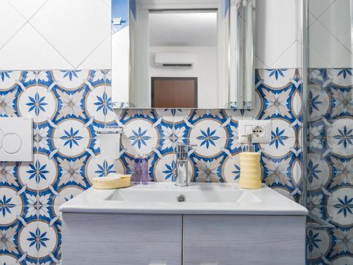 y baño con lavabo y paredes de azulejos azules y blancos. en Casa Alessandra - De Vivo Realty Positano, en Positano
