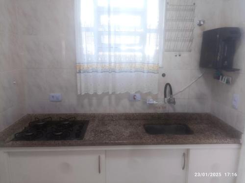 un comptoir de cuisine avec un évier et une cuisinière dans l'établissement Casa Centro de Bertioga - SP terrea 300 metros da praia - Marcondes 05, à Bertioga