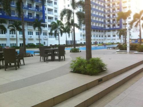 un patio con tavolo, sedie e palme di Sea Residences - Rheiyn a Manila