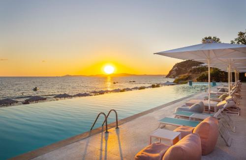 a swimming pool with chairs and the ocean at sunset at Mount Athos Resort in Ierissos