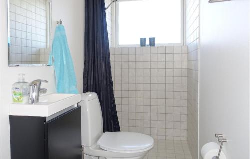 a bathroom with a toilet and a sink and a window at Nice Home In Nexø With Wifi in Neksø