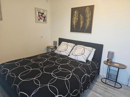 ein Schlafzimmer mit einem schwarz-weißen Bett und zwei Tischen in der Unterkunft F2 neuf tout confort proche Epinal/ lac de Bouzey in Uxegney