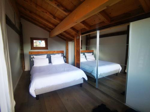 2 bedden in een kamer met houten plafonds bij Le chalet Leïla in Manigod