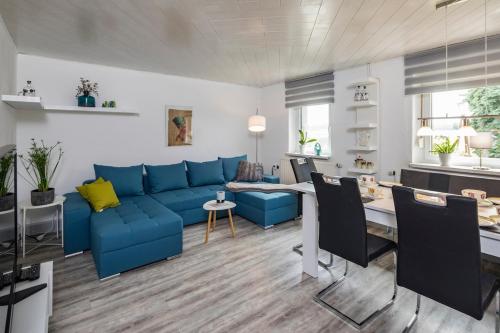 a living room with a blue couch and a table at Dreiseitenhof in ruhiger Lage Haus Gottfriede in Neukirch