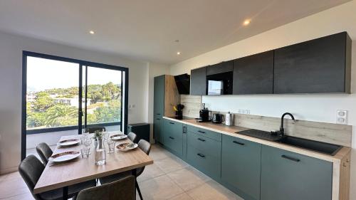 - une cuisine avec une table, des chaises et un évier dans l'établissement Appartement vue mer panoramique & plage à pied Porticcio, à Grosseto-Prugna