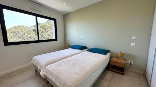 une chambre avec deux lits et une fenêtre dans l'établissement Appartement vue mer panoramique & plage à pied Porticcio, à Grosseto-Prugna