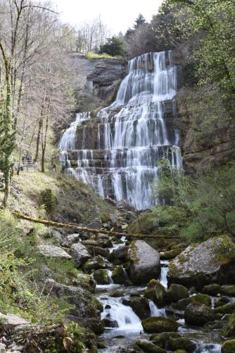 a waterfall on the side of a hill with rocks at La Chalentine in Chevreaux