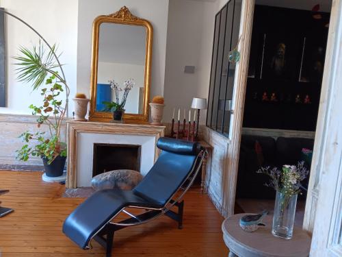 - un fauteuil en cuir noir dans le salon avec un miroir dans l'établissement The Appart 90m2 au coeur de la vieille ville, à La Rochelle