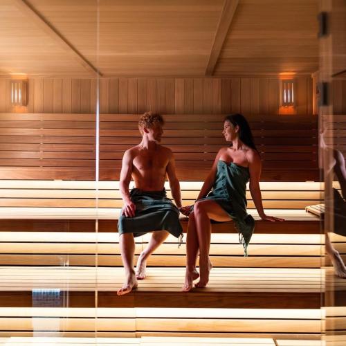 a man and a woman sitting in a sauna at Aura Medical SPA Nałęczów in Nałęczów