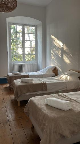 - une rangée de lits dans une chambre avec fenêtre dans l'établissement Château de Savignac, à Savignac