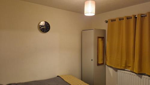 ティプトンにあるEJ Suitesの壁に時計、冷蔵庫が備わる客室です。