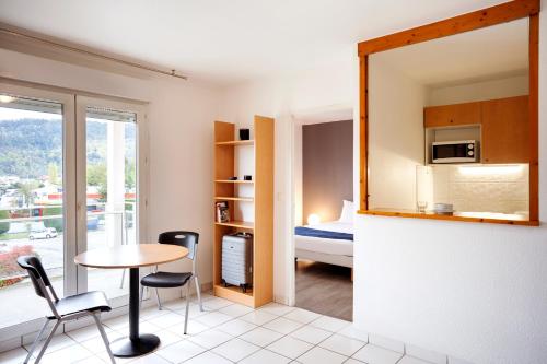 une pièce avec une table et des chaises et une chambre dans l'établissement Séjours & Affaires Annecy Le Pont Neuf, à Annecy
