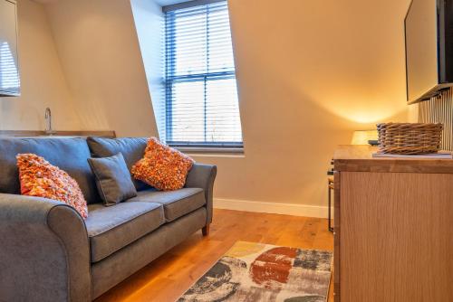 a living room with a blue couch and two windows at Finest Retreats - Nelly's Nook in Matlock