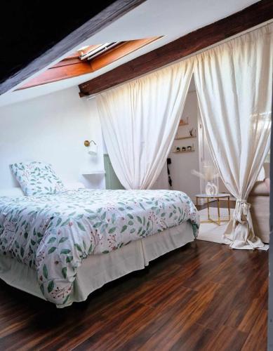 Cette chambre comprend un lit avec des rideaux et du parquet. dans l'établissement Chez Denise Studio Cosy Lyon, à Lyon