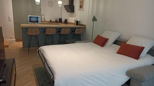 une chambre avec un grand lit blanc et une cuisine dans l'établissement Appartement Vaux le Vicomte, à Boissettes