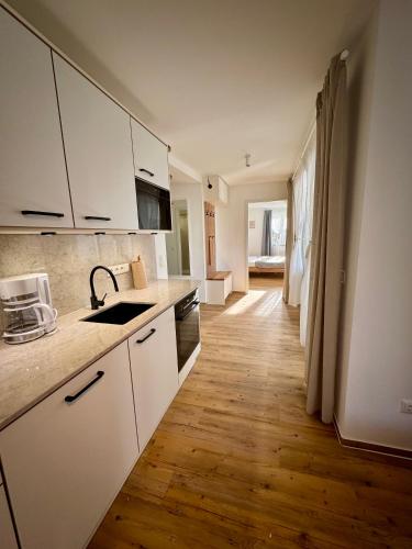 a kitchen with white cabinets and a wooden floor at S4 FeWo in Bad Saarow, Seestr 4a in Bad Saarow