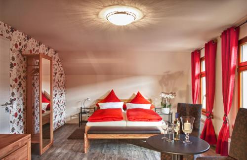 a bedroom with red pillows on a bed with a table at Gästezimmer im FamilienWeingut Räder in Hillesheim