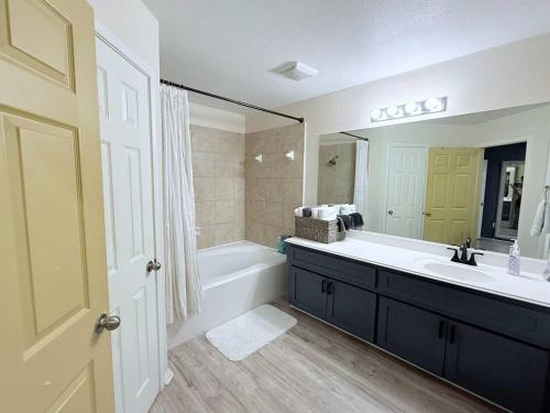 a bathroom with a tub and a sink and a mirror at EaDo Townhome Pool Table By Convention & Stadiums in Houston