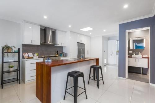 a kitchen with a counter and two bar stools at The perfect family escape modern huge backyard in Perth