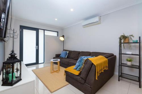 a living room with a brown couch and a yellow blanket at The perfect family escape modern huge backyard in Perth