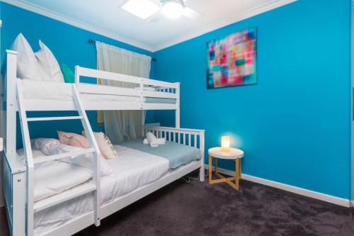 a bedroom with two bunk beds and a blue wall at The perfect family escape modern huge backyard in Perth