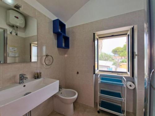 un bagno con lavandino, WC e finestra di Villa Vieste a Vieste