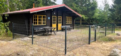 a small wooden cabin with a table and a fence at Bernsteinsee Hotel&Ferien in Sassenburg