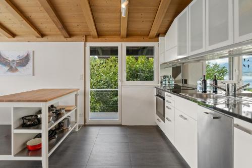 a kitchen with white cabinets and a wooden ceiling at Juwel mit Traumsicht auf See und Berge! in Gunten