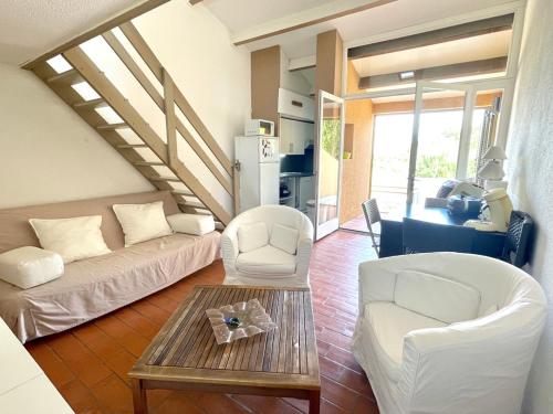 Il comprend un salon doté d'un mobilier blanc et d'un escalier. dans l'établissement Maison 5 pers - vue étang - nature - piscine, à Fitou