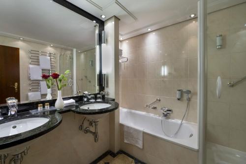 a bathroom with two sinks and a shower and a tub at Maritim Hotel Bellevue Kiel in Kiel