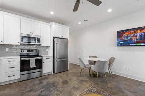 a kitchen with white cabinets and a table with chairs at NEW Acadian House KING Bed Cajun Luxury Nespresso in Lafayette