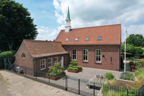 a small brick church with a steeple on top at B&B Het Schipperskerkje in Tolkamer