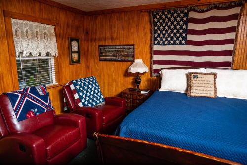 a bedroom with a bed and a chair and an american flag at Mountain Aire Cottages, Inn, & Glamping in Clayton
