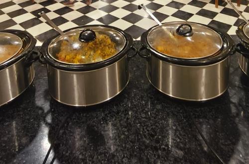 eine Gruppe von drei Töpfen, die mit Lebensmitteln auf einer Theke gefüllt sind in der Unterkunft Desert Popular Resort & Camp in Jaisalmer