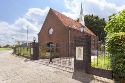 an old brick church with a fence and a steeple at B&B Het Schipperskerkje in Tolkamer