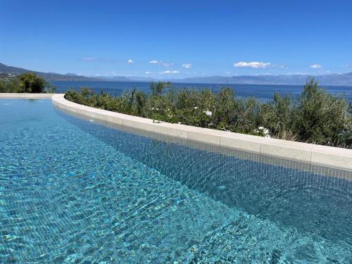 a swimming pool with blue water and a view of the ocean at Akria Thea in Koroni