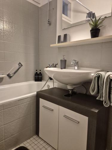 a white bathroom with a sink and a bath tub at Wasserfälle Apartments in Sasbachwalden