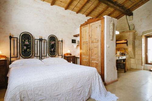 a bedroom with a white bed and a wooden door at Borgoterra in Martano