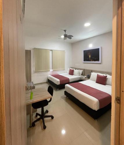a hotel room with two beds and a desk at Hotel Rosales Boutique in Neiva