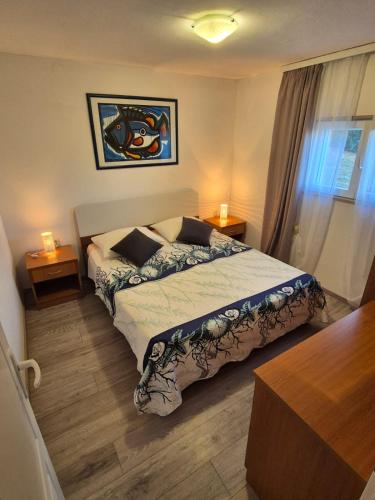a bedroom with a bed and two tables and a window at Apartments Buktenica in Bol